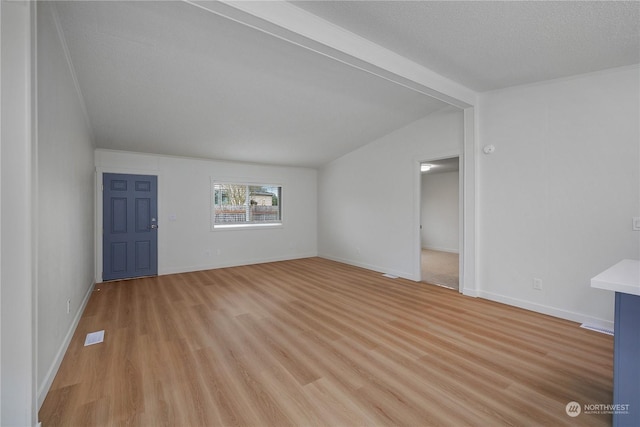 unfurnished living room featuring vaulted ceiling with beams, a textured ceiling, and light hardwood / wood-style flooring