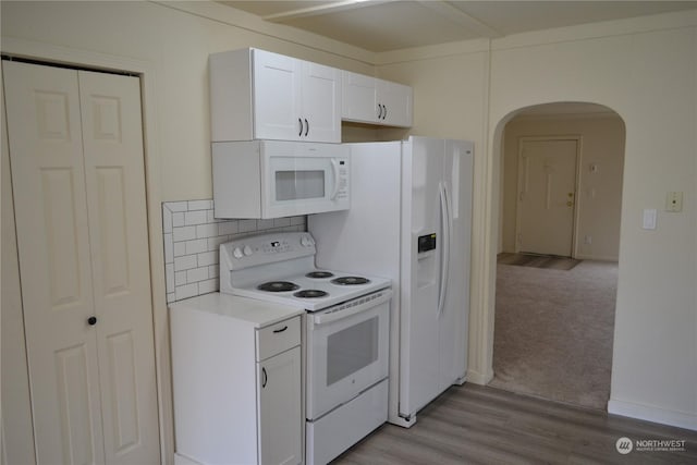 kitchen with white appliances, light carpet, backsplash, and white cabinets