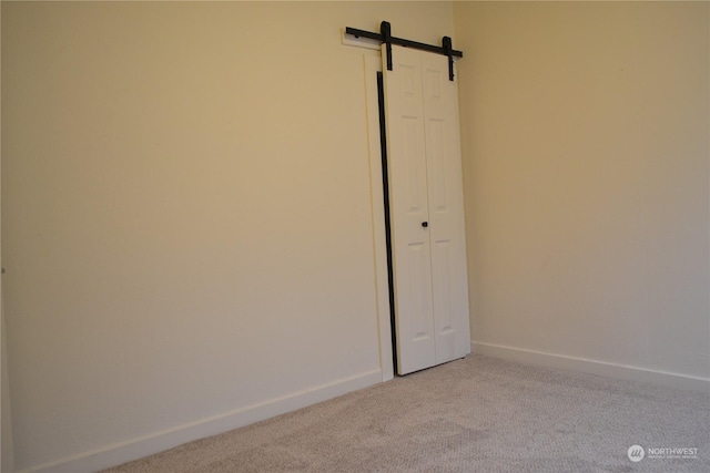 carpeted empty room featuring a barn door