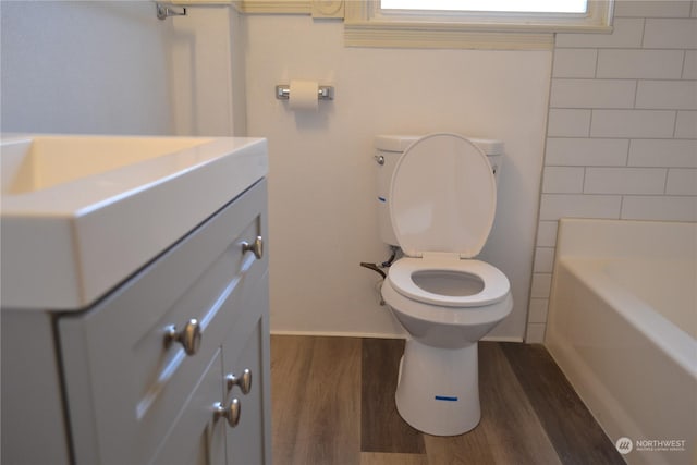 bathroom with a bathtub, vanity, toilet, and hardwood / wood-style flooring