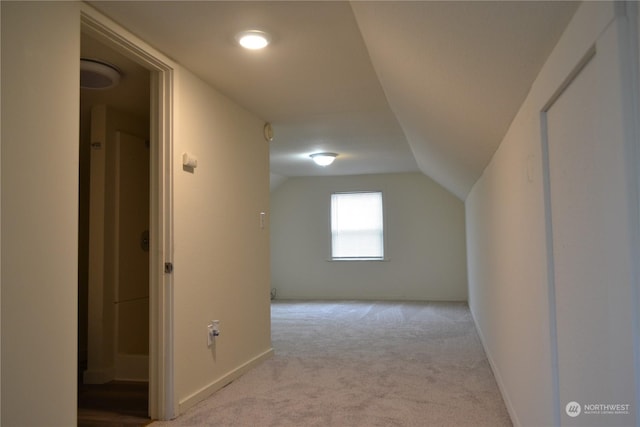 bonus room with lofted ceiling and light carpet