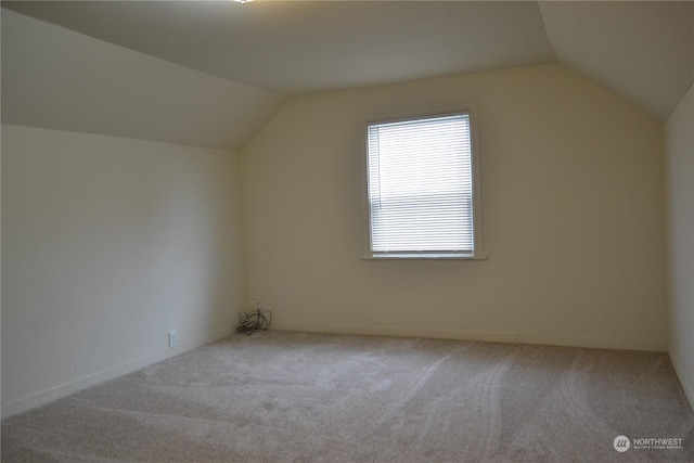 bonus room with vaulted ceiling and light colored carpet