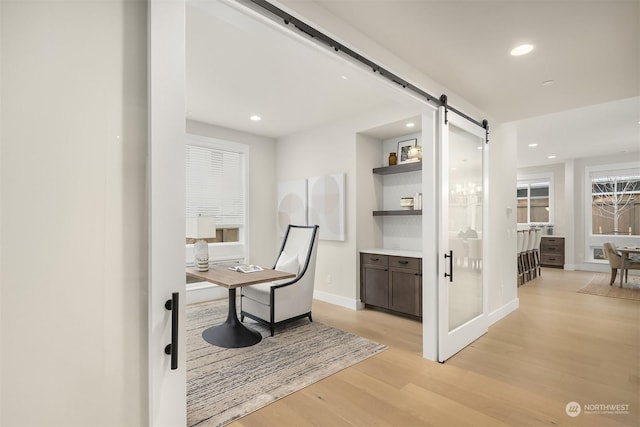 office area with a barn door and light hardwood / wood-style flooring