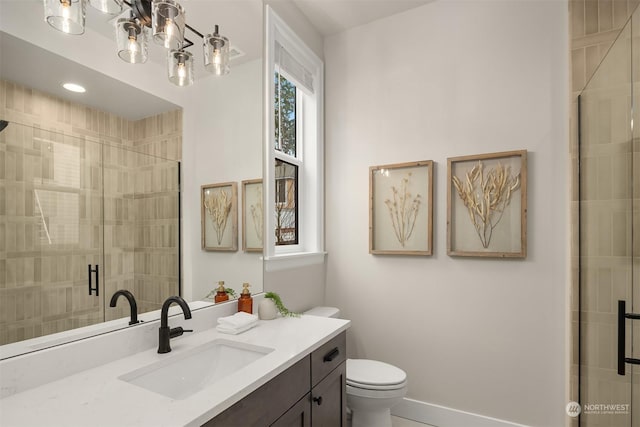 bathroom featuring toilet, vanity, and a shower with shower door