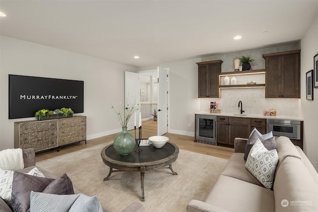 living room with light wood-type flooring, wine cooler, and sink