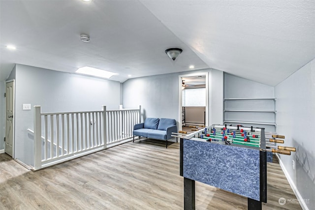 game room with a textured ceiling, hardwood / wood-style floors, and vaulted ceiling with skylight