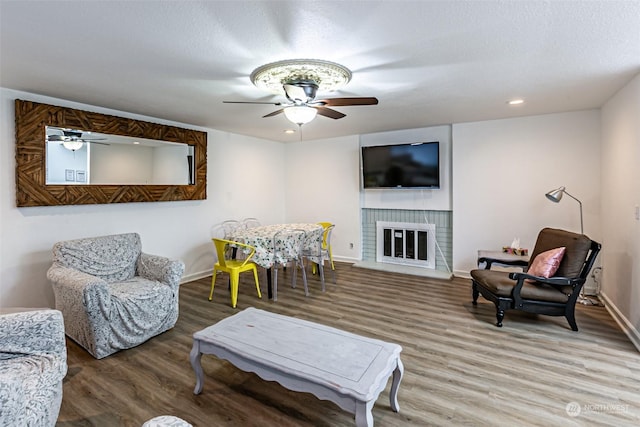 living room featuring hardwood / wood-style flooring, a textured ceiling, ceiling fan, and a fireplace