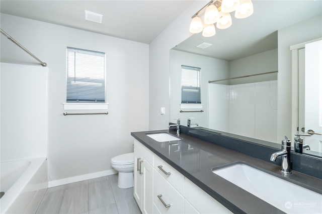 bathroom featuring double vanity, toilet, baseboards, and a sink