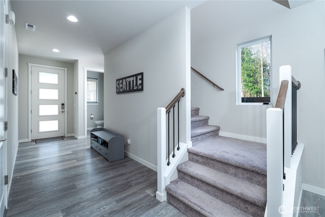 entrance foyer featuring visible vents, baseboards, wood finished floors, and stairs