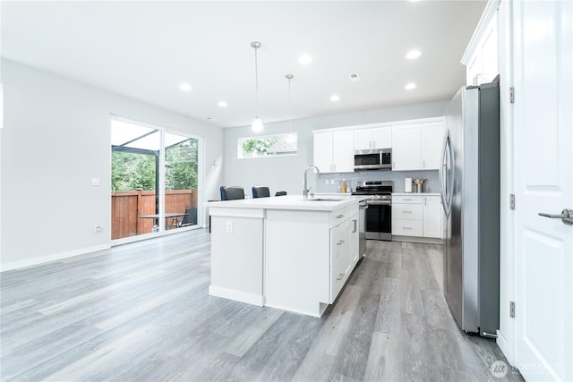 kitchen with decorative backsplash, appliances with stainless steel finishes, light wood-style floors, and a sink