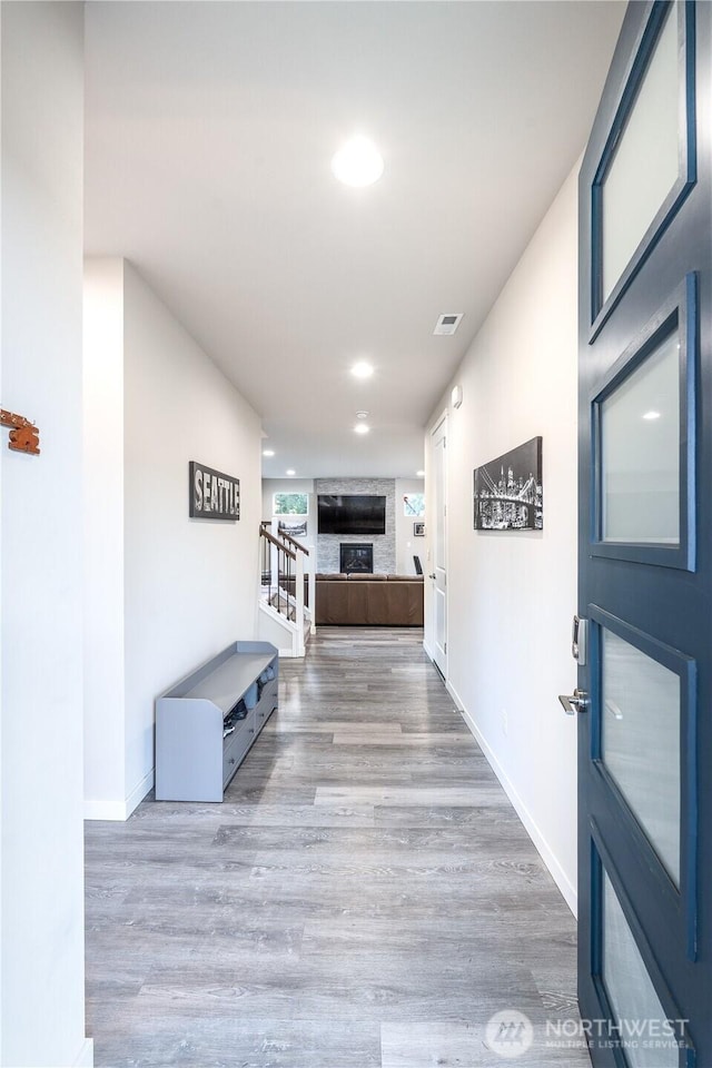 hall featuring stairway, baseboards, visible vents, and wood finished floors