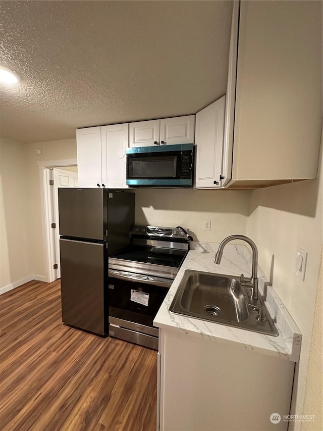 kitchen featuring sink, white cabinetry, a textured ceiling, dark hardwood / wood-style flooring, and stainless steel appliances