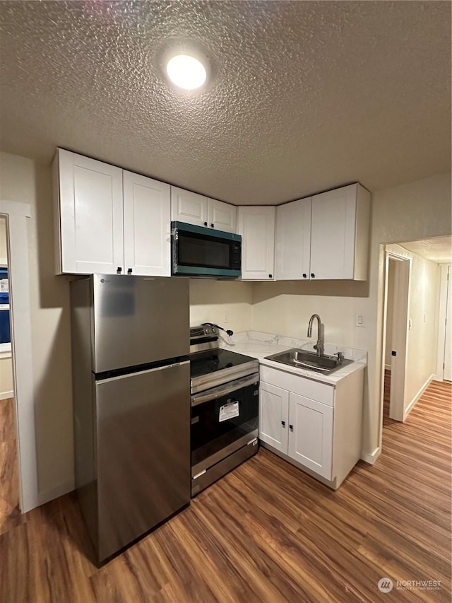 kitchen featuring dark hardwood / wood-style flooring, sink, white cabinets, and appliances with stainless steel finishes