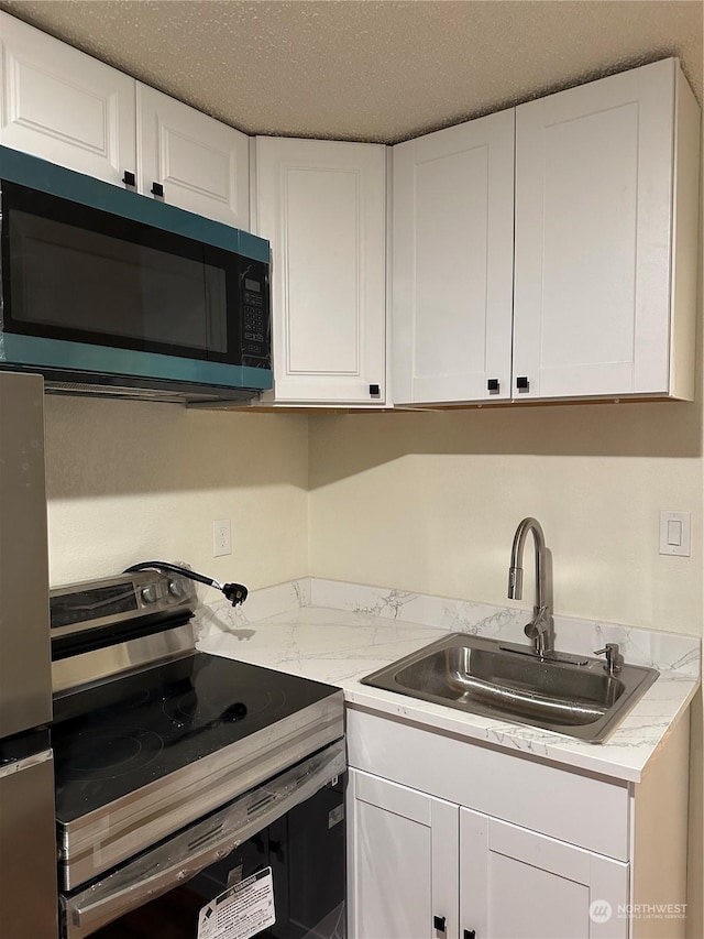 kitchen with sink, white cabinetry, a textured ceiling, stainless steel electric stove, and light stone countertops