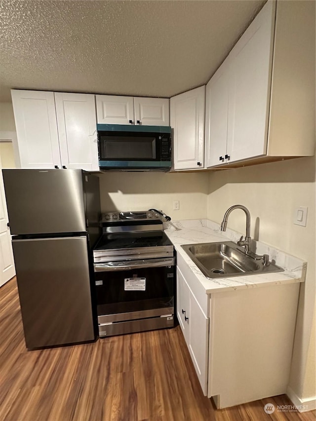 kitchen with stainless steel appliances, white cabinetry, sink, and dark wood-type flooring