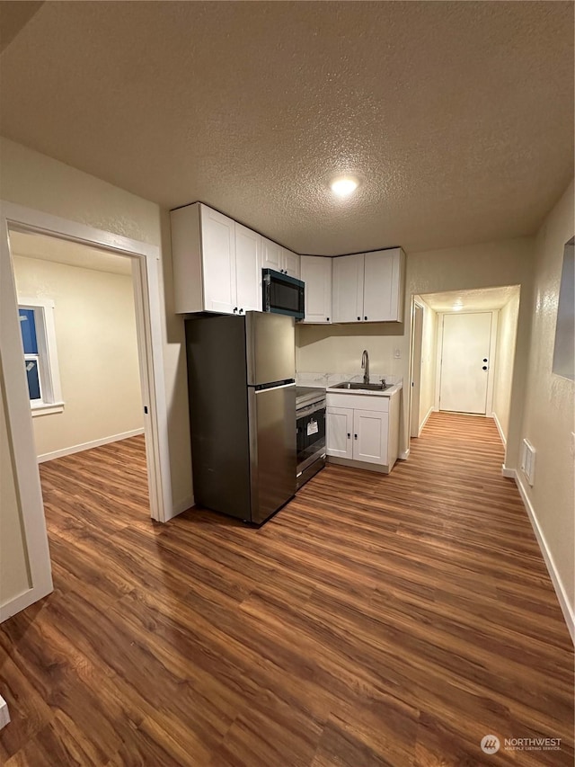 kitchen with dark hardwood / wood-style floors, stove, stainless steel fridge, and white cabinets