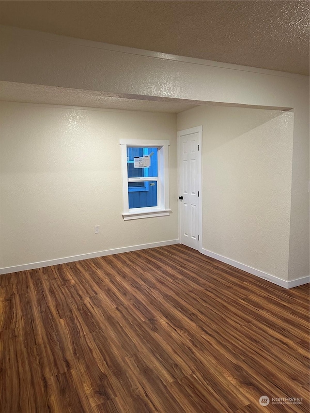 unfurnished room with dark hardwood / wood-style flooring and a textured ceiling