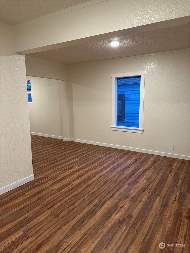 empty room featuring a textured ceiling and dark hardwood / wood-style flooring