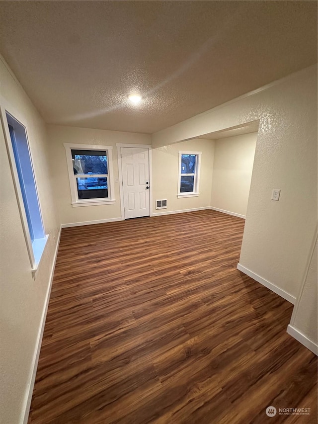 spare room featuring dark wood-type flooring and a textured ceiling