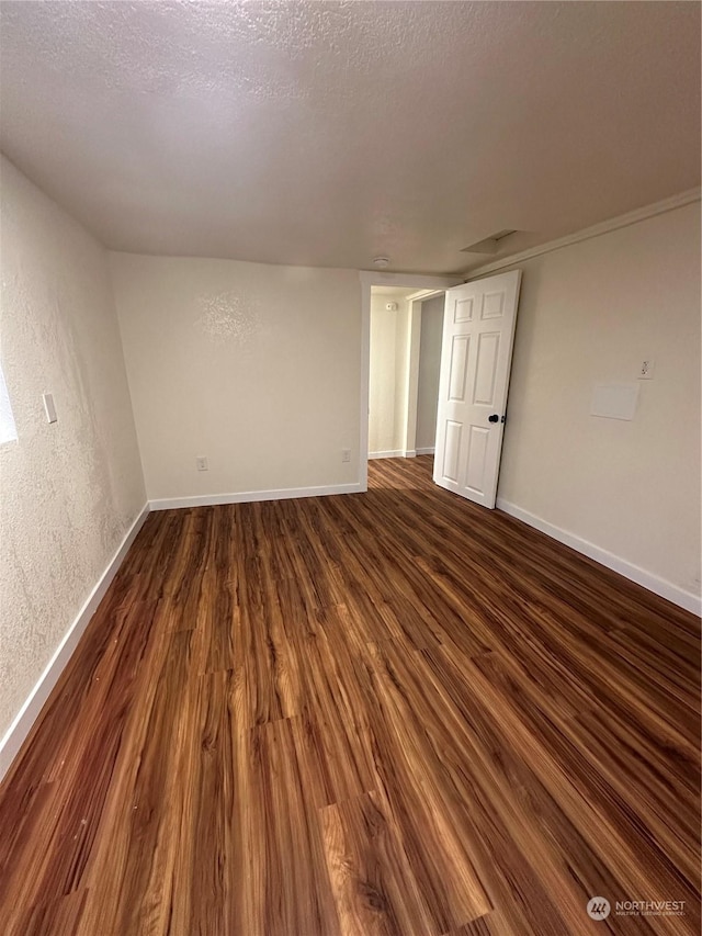 unfurnished room featuring dark wood-type flooring and a textured ceiling