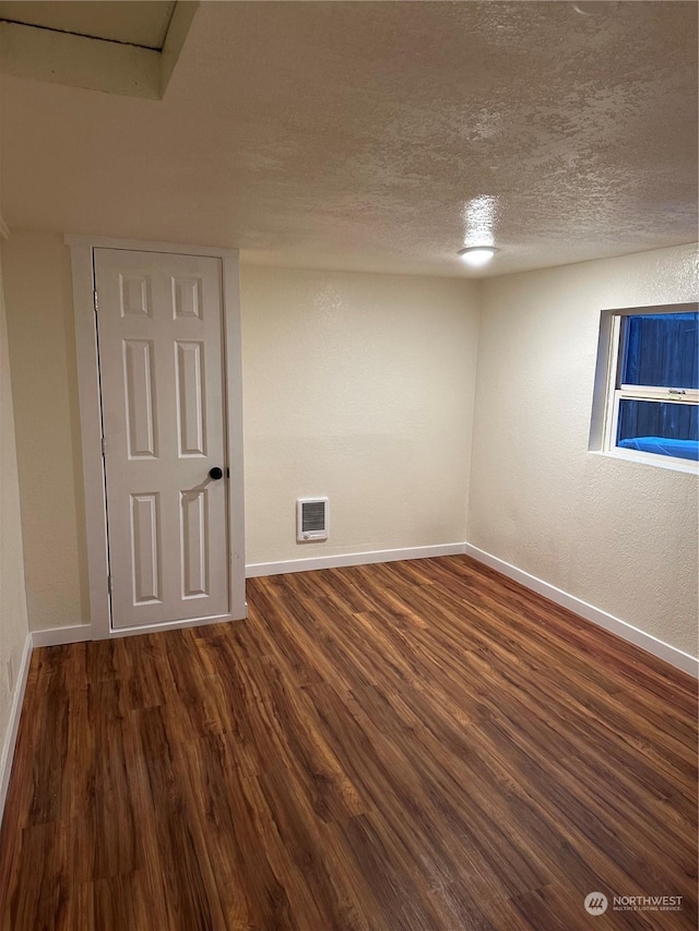 unfurnished room featuring dark hardwood / wood-style floors and a textured ceiling