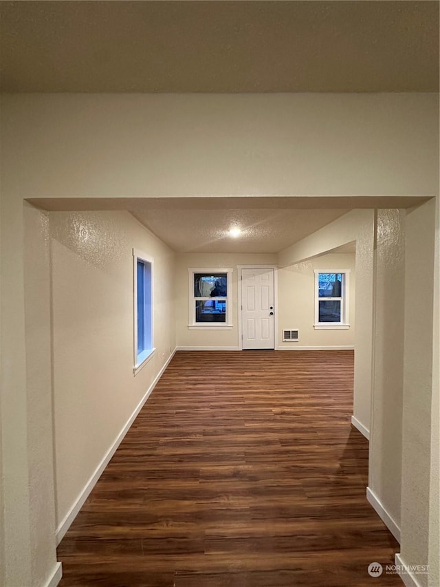 corridor with dark hardwood / wood-style flooring and a textured ceiling