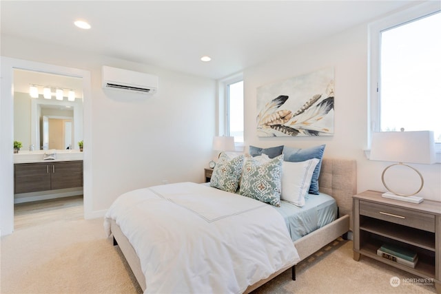 bedroom featuring light carpet, an AC wall unit, and ensuite bath