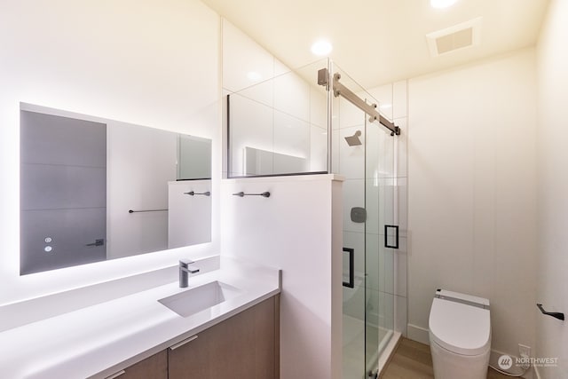 bathroom featuring wood-type flooring, toilet, walk in shower, and vanity