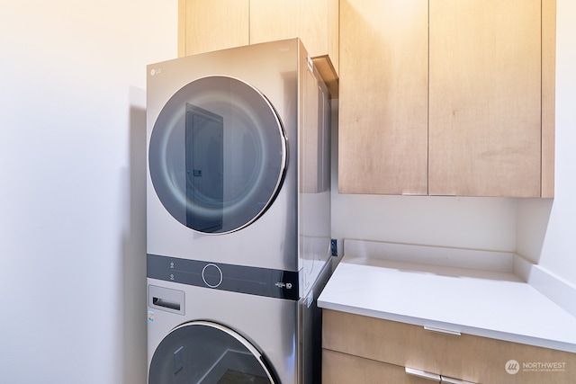 washroom with cabinets and stacked washer / dryer