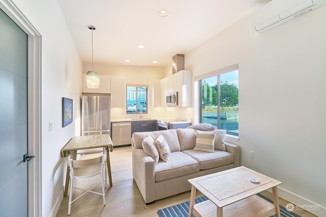 living room with sink, light hardwood / wood-style flooring, and a wall unit AC