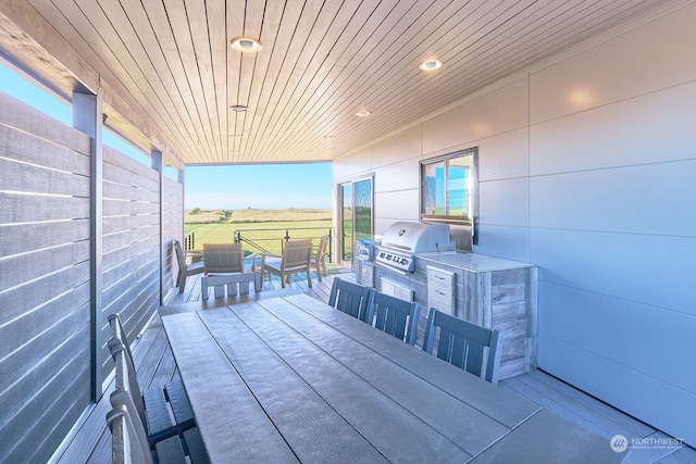 wooden terrace with exterior kitchen, a rural view, and area for grilling