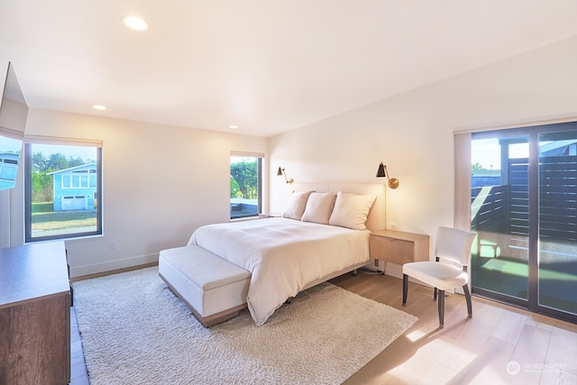 bedroom featuring access to exterior, multiple windows, and light hardwood / wood-style flooring