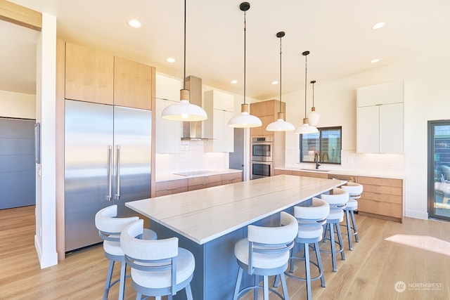 kitchen with decorative light fixtures, a center island, sink, white cabinetry, and appliances with stainless steel finishes