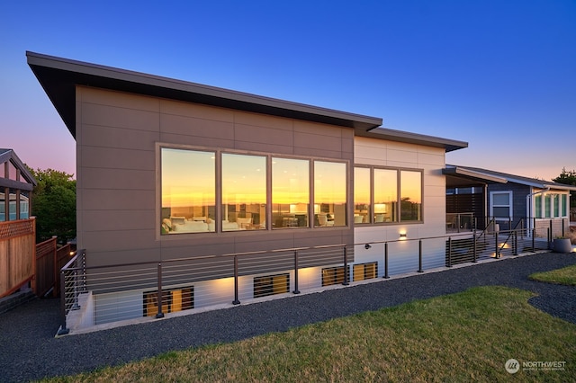 back house at dusk with a lawn