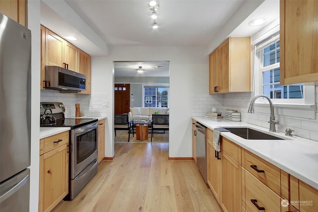 kitchen with stainless steel appliances, light hardwood / wood-style flooring, tasteful backsplash, and sink