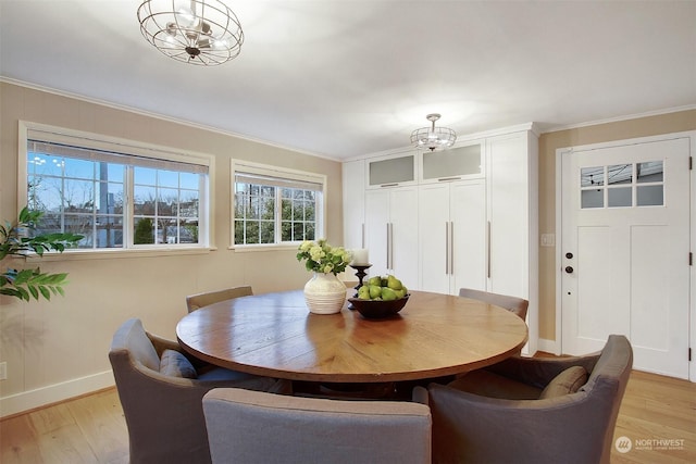 dining area with a chandelier, ornamental molding, and light hardwood / wood-style flooring