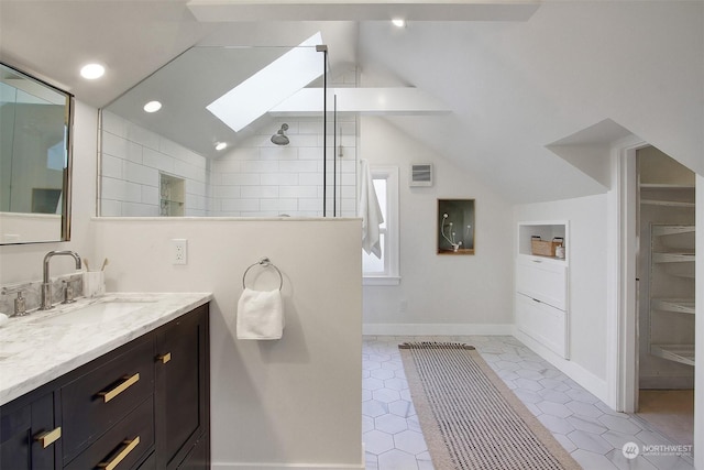 bathroom with vaulted ceiling with skylight, tile patterned flooring, tiled shower, and vanity