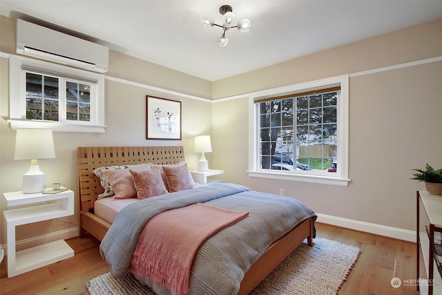 bedroom with light hardwood / wood-style flooring and a wall mounted AC