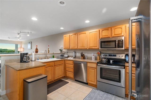 kitchen with light stone counters, stainless steel appliances, light brown cabinetry, light tile patterned flooring, and sink