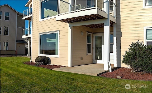 view of exterior entry featuring a yard and a patio area