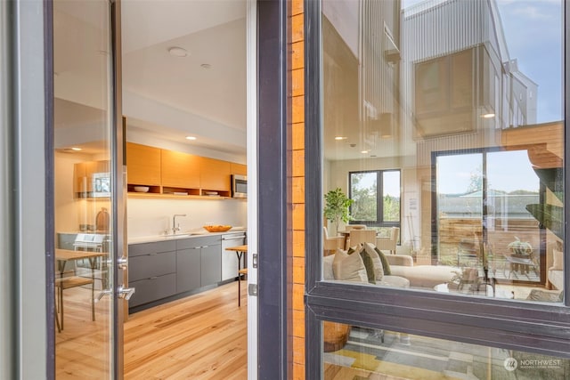 doorway to outside with light hardwood / wood-style floors and sink