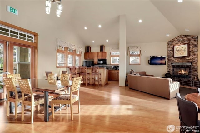 dining area with a stone fireplace, visible vents, plenty of natural light, and light wood-style flooring