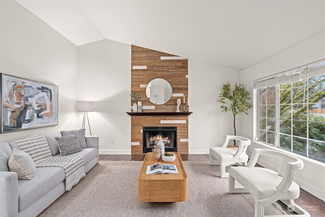 living room featuring lofted ceiling, a tiled fireplace, wood walls, and hardwood / wood-style floors