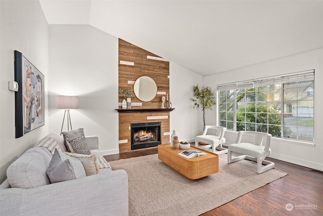 living room with dark hardwood / wood-style flooring, vaulted ceiling, and a fireplace