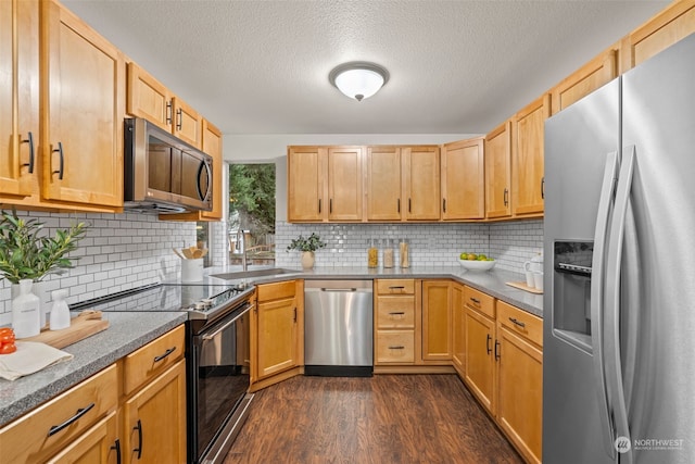 kitchen featuring appliances with stainless steel finishes, dark wood-type flooring, decorative backsplash, a textured ceiling, and sink