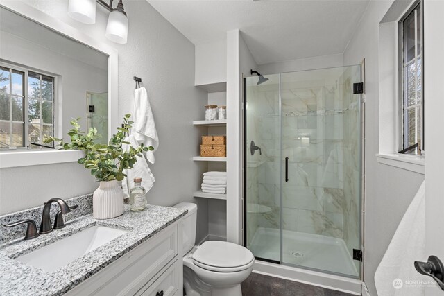 bathroom with toilet, a shower with door, and vanity