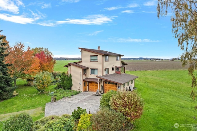 view of front of property with a front lawn, a rural view, and a garage