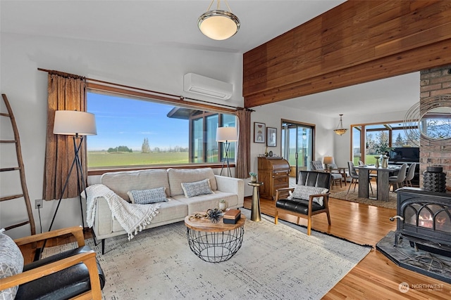 living room with wood-type flooring, vaulted ceiling, a wood stove, and an AC wall unit