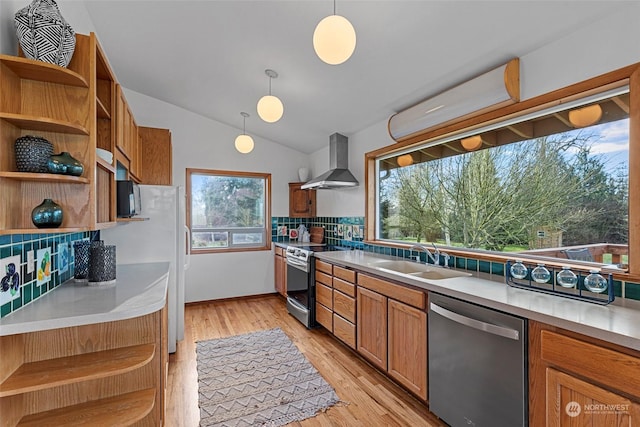 kitchen featuring decorative light fixtures, stainless steel appliances, wall chimney range hood, backsplash, and sink