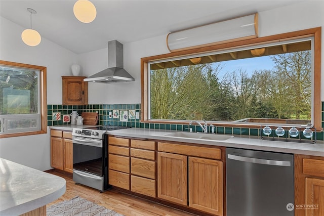 kitchen featuring stainless steel appliances, sink, wall chimney exhaust hood, tasteful backsplash, and hanging light fixtures